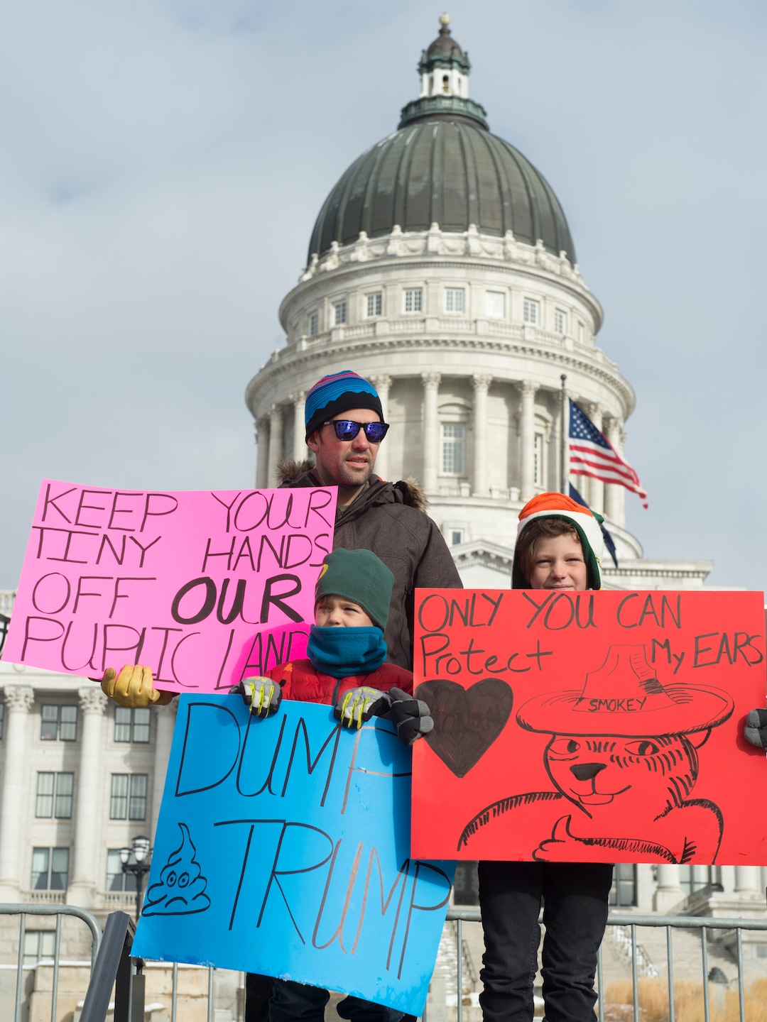 (Rick Egan  |  The Salt Lake Tribune) Perry Dixon, stands with his kids Miles, 6, and Parker 9, as they protest President Trump's visit to Utah to shrink the Bears Ears monument in front of the Utah State Capitol Building, Monday, December 4, 2017.