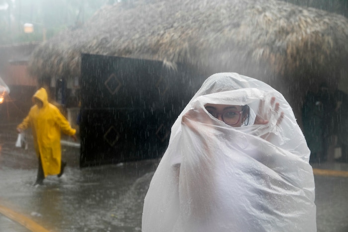 In this Sept. 20, 2017 photo, a woman covers herself with a plastic bag as she makes her way to work as Hurricane Maria approaches the coast of Bavaro, Dominican Republic. (AP Photo/Tatiana Fernandez)