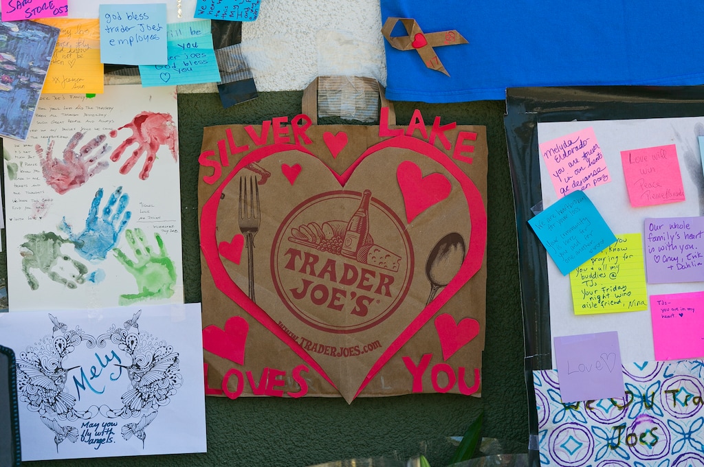 (Damian Dovarganes | The Associated Press) A heart-shaped card made with a recycled Trader Joe's paper bag is posted by a makeshift memorial of flowers, candles and notes on the sidewalk outside the Silver Lake Trader Joe's store in Los Angeles, Monday, July 23, 2018. On Saturday, Trader Joe's worker Melyda Corado was shot and killed in an exchange of gunfire between a suspect and police at the store. Grieving family members, co-workers and customers on Sunday remembered Corado as lively, hardworking and always smiling.