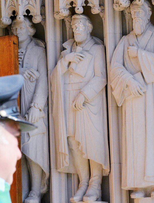 FILE - In this Aug. 17, 2017 file photo, the defaced Gen. Robert E. Lee statue, center, stands at the Duke Chapel in Durham, N.C. Duke  Duke University removed a statue of Gen. Robert E. Lee early Saturday, Aug. 19, days after it was vandalized amid a national debate about monuments to the Confederacy.  The university said it removed the carved limestone likeness early Saturday morning from Duke Chapel where it stood among 10 historical figures depicted in the entryway  (Bernard Thomas/The Herald-Sun via AP, File)