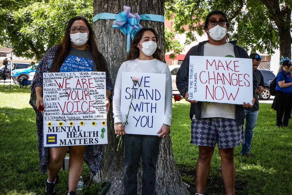 (Nancy Newberry for The New York Times) 

UVALDE, Texas  — Young adults holding signs near the memorial in Uvalde, Texas.