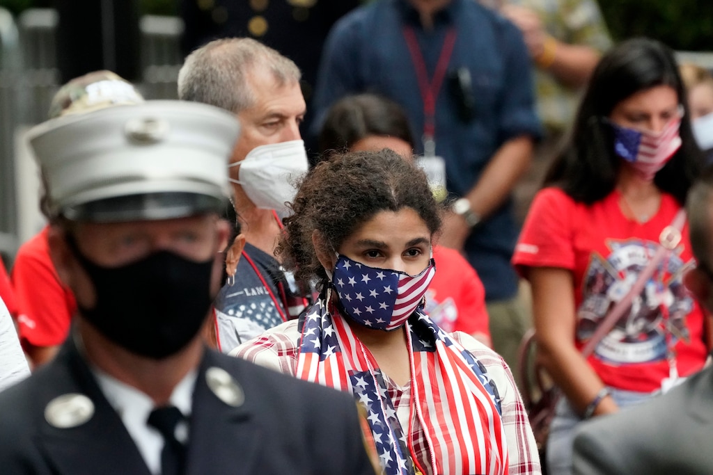 A woman wearing a flag mask joins others in prayer at the Tunnel to Towers ceremony, Sept. 11, 2020, in New York. Vice President Mike Pence and his wife Karen will attend the ceremony where the names of nearly 3,000 victims of the Sept. 11, 2001 terror attacks will be read by family members. (AP Photo/Mark Lennihan)