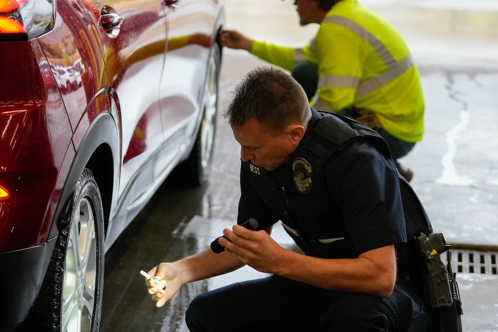 (Francisco Kjolseth | The Salt Lake Tribune) Cottonwood Heights officer Lance Bess helps with tire inspection as people line up to participate in the free and voluntary Cottonwood Canyon’s sticker distribution kick-off event to comply with traction devices required during severe weather this winter on Thursday, Oct. 17, 2024. The Utah Department of Transportation is partnering with local law enforcement from Cottonwood Heights and Sandy to increase traction law enforcement.