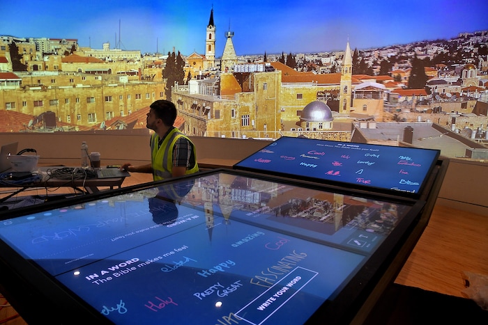 Senior software developer Donnie Richardson is still doing testing at the area (foreground) where visitors to the Museum of the Bible can write on a large interactive tablet table. Those messages will be shown on the big screen in the background (now featuring a panoramic photo of Jerusalem). MUST CREDIT: Washington Post photo by Michael S. Williamson.