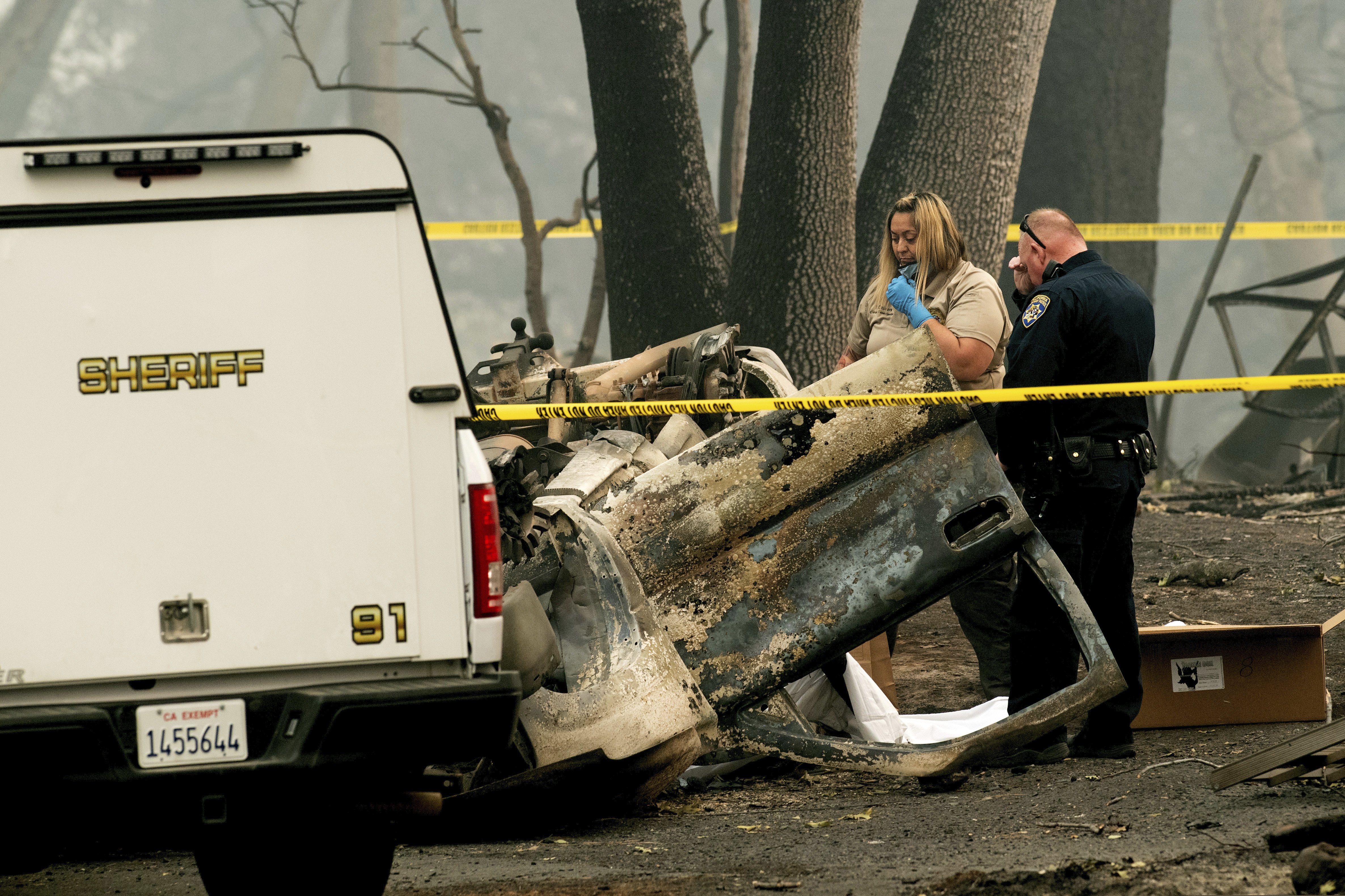 A sheriff's deputy recovers the remains of a Camp Fire victim from an overturned car in Paradise, Calif., on Thursday, Nov. 15, 2018. (AP Photo/Noah Berger)