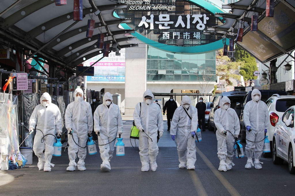 (Im Hwa-young/Yonhap via AP) Workers wearing protective gears spray disinfectant as a precaution against the COVID-19 at a local market in Daegu, South Korea, Sunday, Feb. 23, 2020. South Korea's president has put the country on its highest alert for infectious diseases and says officials should take "unprecedented, powerful" steps to fight a viral outbreak.