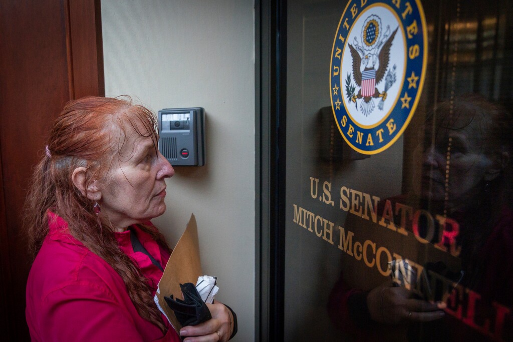 Reese Greer, a furloughed census worker, stands at the locked door of U.S. Sen. Mitch McConnell's office in Lexington, Ky., Wednesday, Jan 23, 2019, during a government shutdown protest. (AP Photo/Bryan Woolston)