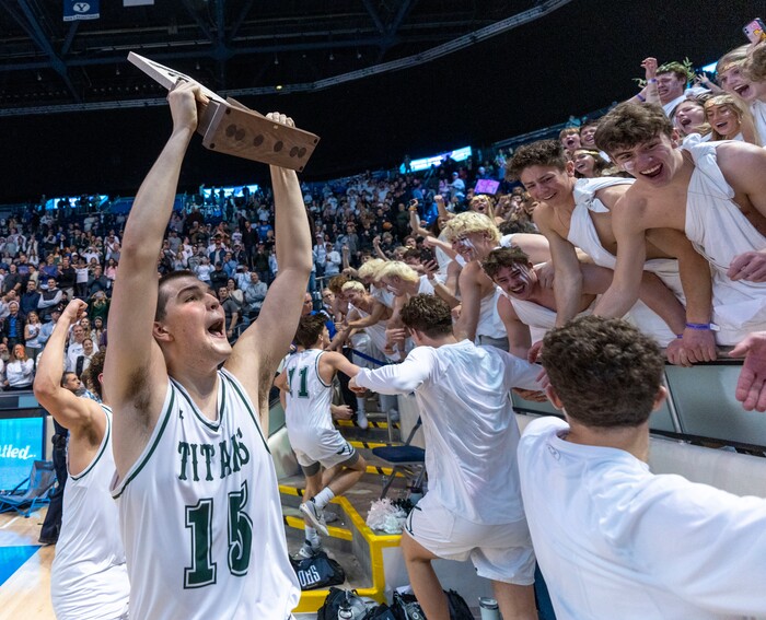 (Rick Egan | The Salt Lake Tribune) 
Olympus Titan, center, Jack Wistrcill (15 holds up the State Championship tophy as the Olympus titans celebrate their win in the 5A State Championship game between Woods Cross and Olympus, at the Marriott Center in Provo, on Saturday, March 5, 2022. 