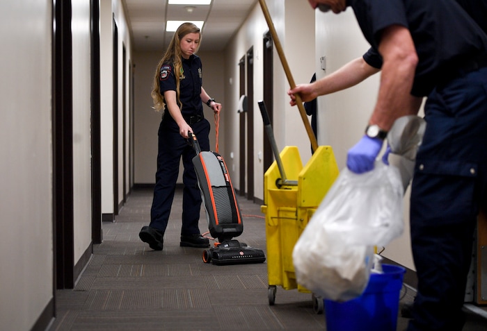 In this Jan. 19, 2018, photo, Lehi firefighter and paramedic Aubrey Freiberg vacuums as she and other firefighters clean at Station 82 of the Lehi Fire Department in Lehi, Utah. (Isaac Hale/The Daily Herald via AP)