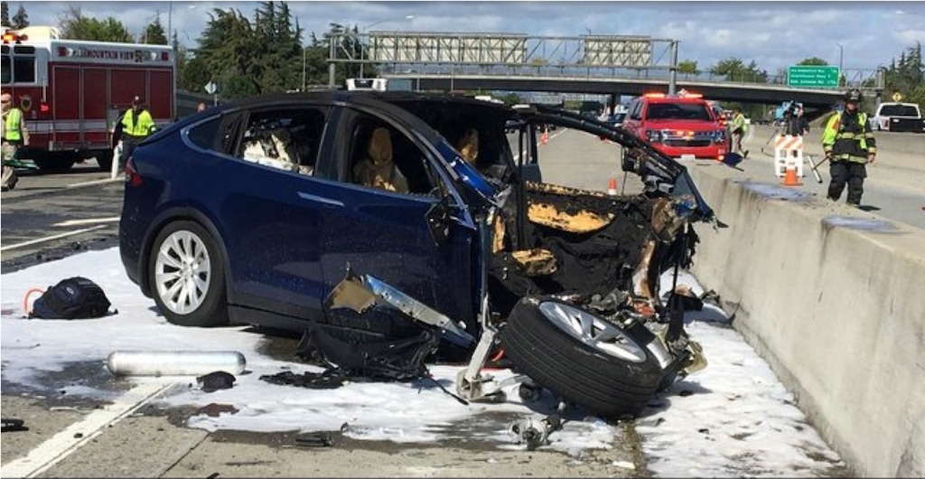 In this Friday March 23, 2018 photo provided by KTVU, emergency personnel work a the scene where a Tesla electric SUV crashed into a barrier on U.S. Highway 101 in Mountain View, Calif. The National Transportation Safety Board has sent two investigators to look into a fatal crash and fire Friday in California that involved a Tesla electric SUV. The agency says on Twitter that it's not clear whether the Tesla Model X was operating on its semi-autonomous control system called Autopilot at the time. Investigators will study the fire that broke out after the crash. (KTVU via AP)