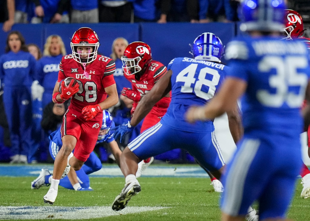(Bethany Baker | The Salt Lake Tribune) Utah Utes wide receiver Mana Carvalho (28) runs the ball as BYU Cougars linebacker Bodie Schoonover (48) and BYU Cougars safety Jarinn Kalama (35) defend during the game between the BYU Cougars and the Utah Utes in Provo on Saturday, Oct. 18, 2025.