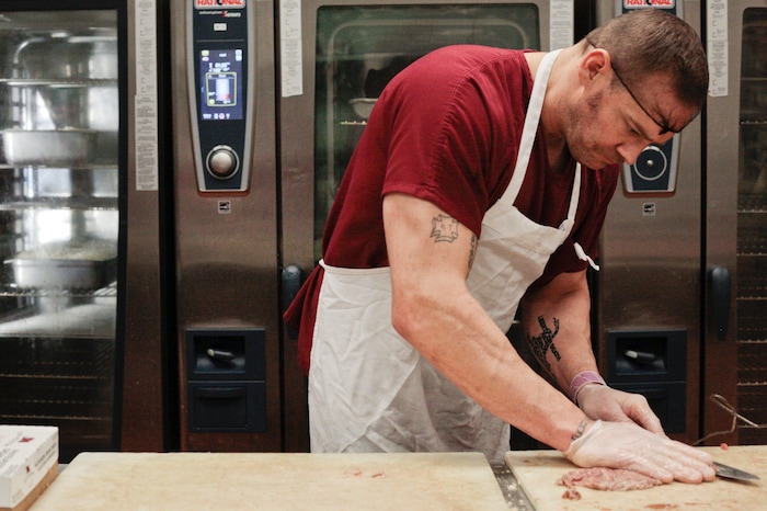 In this photo taken Jan. 26, 2018, Joe Byington cuts meat in the kitchen at the Utah County Jail in Spanish Fork, Utah. The Utah County Jail Culinary Arts program utilizes inmates labor in the commercial kitchen. (Evan Cobb/The Daily Herald via AP)