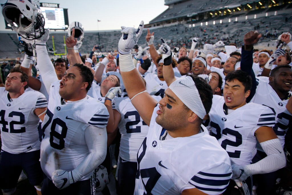 FILE - This Oct. 8, 2016, file photo shows BYU players, including Austin Heder (42), Tuni Kanuch (78), Kesni Tausinga (94) and Hiva Lee, right, celebrate following a 31-14 win over Michigan State in an NCAA college football game, in East Lansing, Mich. A team can go on the road and play a Power Five conference team and earn $1 million-$2 million, often enough to keep other sports programs afloat or fund the training table or academic center. Perhaps no school faces a bigger challenge than independent BYU, which had five games fall off its schedule — Utah, Michigan State, Arizona State and Minnesota to start the season and a Nov. 28 game against Stanford.(AP Photo/Al Goldis)