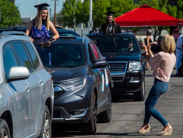(Rick Egan  |  The Salt Lake Tribune)      Natalie DeGering poses as Nicea DeGering snaps a photo as the Alta High 2020 graduates drive by in a “drive through” graduation ceremony at Alta High, Thursday, May 28, 2020.