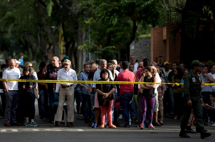 Voters stand behind security tape outside a polling station as they wait to cast their ballots for regional elections in Caracas, Venezuela, Sunday, Oct. 15, 2017. Elections could tilt a majority of the states' 23 governorships back into opposition control for the first time in nearly two decades of socialist party rule, though the government says the newly elected governors will be subordinate to a pro-government assembly. (AP Photo/Fernando Llano)