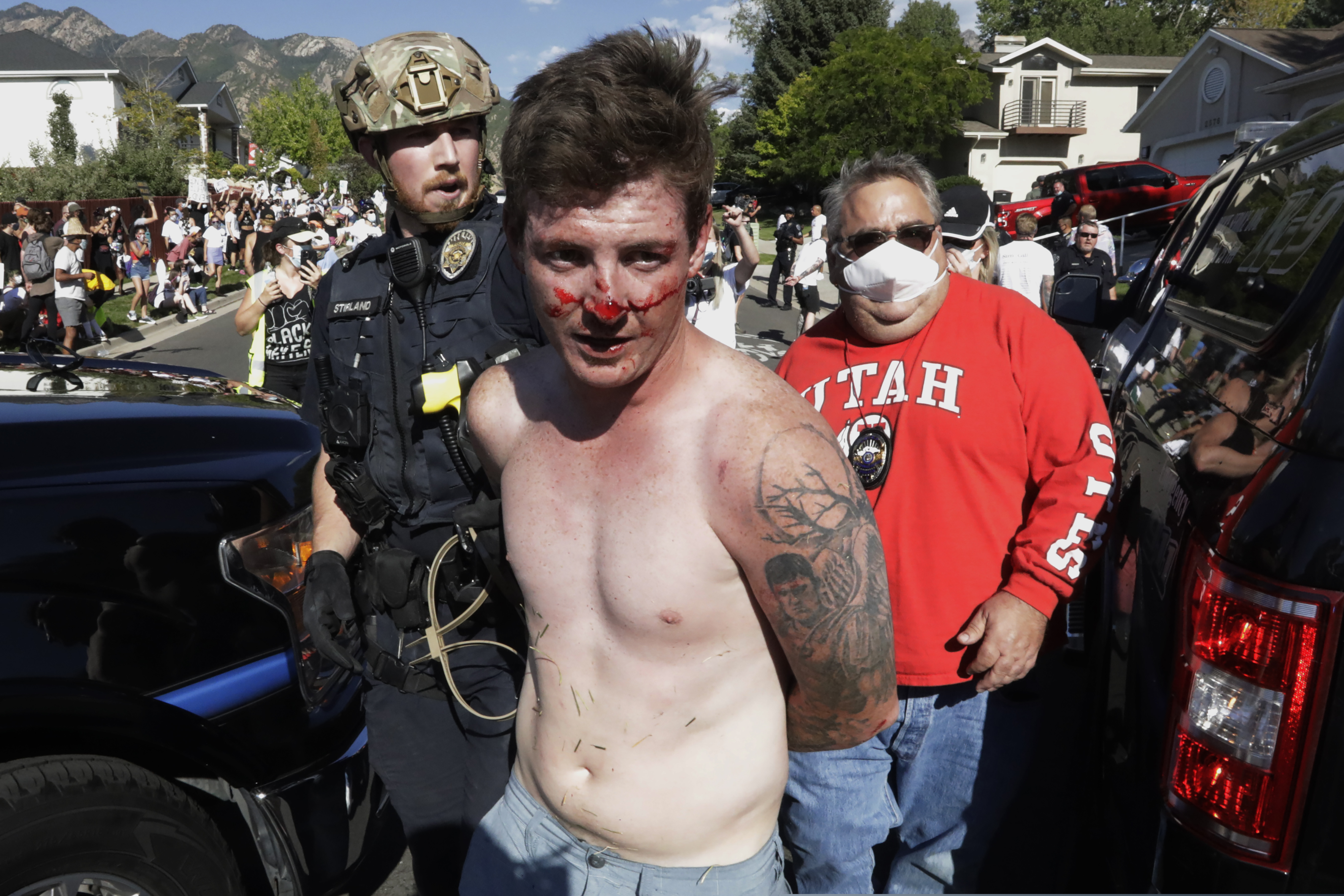 A protester is led away after being taken into custody by Cottonwood Heights police officers during a march Sunday, Aug. 2, 2020, in Cottonwood Heights, Utah. The protest was a "March for Justice" focused largely around Zane James, who was fatally shot by police in Cottonwood Heights in 2018. (AP Photo/Rick Bowmer)