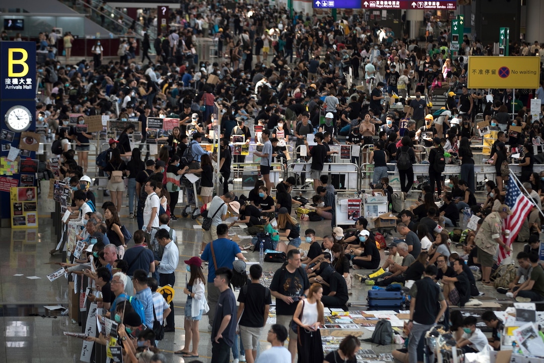 (Vincent Thian | AP Photo) Protesters stage a sit-in rally at the arrival hall of the Hong Kong International Airport in Hong Kong, Tuesday, Aug. 13, 2019. Protesters clogged the departure area at Hong Kong's reopened airport Tuesday, a day after they forced one of the world's busiest transport hubs to shut down entirely amid their calls for an independent inquiry into alleged police abuse.