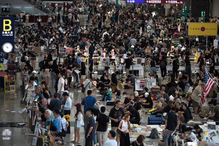 (Vincent Thian | AP Photo) Protesters stage a sit-in rally at the arrival hall of the Hong Kong International Airport in Hong Kong, Tuesday, Aug. 13, 2019. Protesters clogged the departure area at Hong Kong's reopened airport Tuesday, a day after they forced one of the world's busiest transport hubs to shut down entirely amid their calls for an independent inquiry into alleged police abuse.