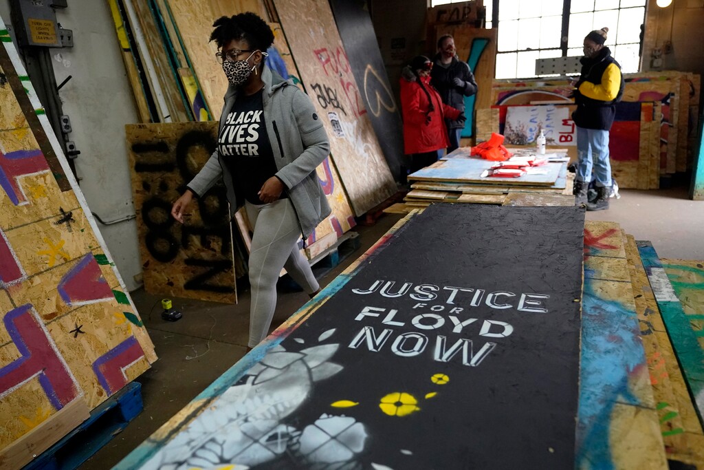 (Jim Mone | The Associated Press) Leesa Kelly, left, walks past plywood mural boards as she and Kenda Zellner-Smith, background right, and volunteers meet at a warehouse, Saturday, Dec. 12, 2020, in Minneapolis to organize them. The two women formed the Save the Boards to Memorialize the Movement to preserve the painted expressions and pain born of outrage after the death of George Floyd at the hands of Minneapolis police in May.