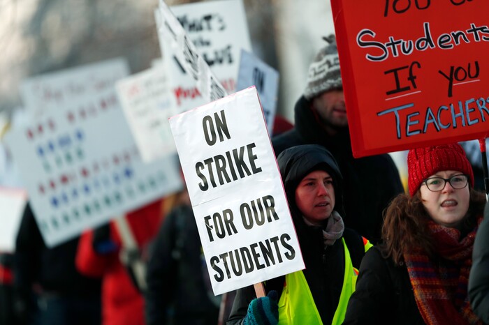 Teachers carry placards as they walk a picket line outside South High School early Monday, Feb. 11, 2019, in Denver. The strike on Monday is the first for teachers in Colorado in 25 years after failed negotiations with the school district over base pay. (AP Photo/David Zalubowski)