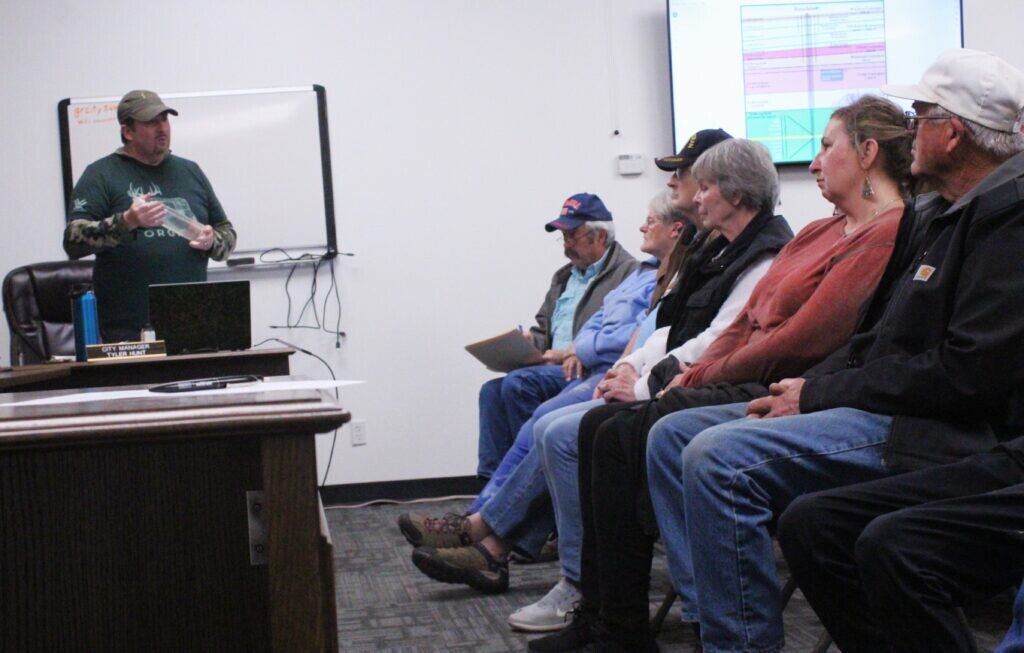 (Sophia Fisher | Moab Times-Independent) Holding a bottle of water that he said came from a test well’s March 8 water surge, A1 Lithium representative Michael Swenson addresses a roomful of residents at the Green River City Hall on Wednesday, March 13.