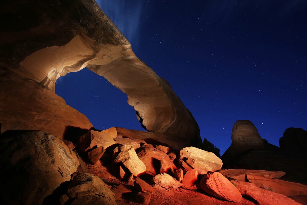 (Francisco Kjolseth | The Salt Lake Tribune) Skyline Arch is lit up at night as the setting sun begins to reveal the sea of stars above during a camping trip to Arches National Park.