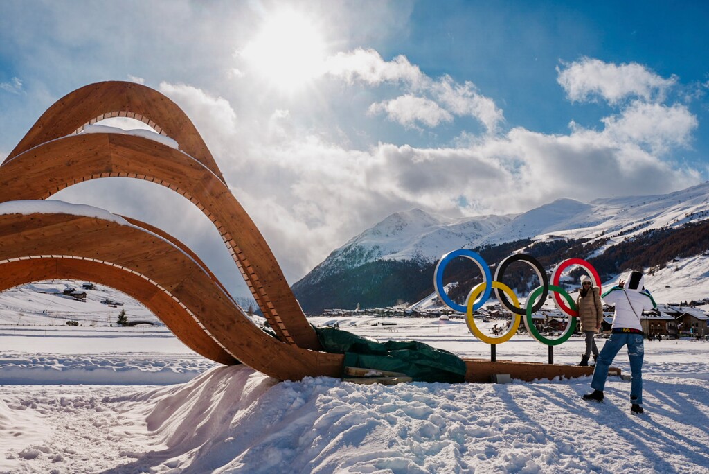 (Gabriela Bhaskar | The New York Times) Visitors take a photo with the Olympic rings at the Livigno Snow Park, which will host the Big Air, Slope Style, Half Pipe and Ski Cross events of the 2026 Milan Cortina Winter Olympics, in Livigno, Italy, on Tuesday, Feb. 3, 2026.