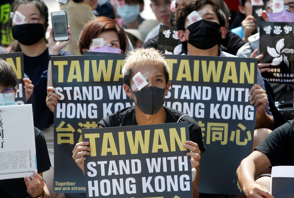 Hong Kong students living in Taiwan and Taiwanese supporters with their eyes covered in red-eyepatch, symbolizing a women reported to have had an eye ruptured by a beanbag round fired by police during clashes, hold slogans during a rally in Taipei, Taiwan, Saturday, Aug. 17, 2019. More than 100 people gathered to support Hong Kong's pro-democracy protesters. (AP Photo/Chiang Ying-ying)
