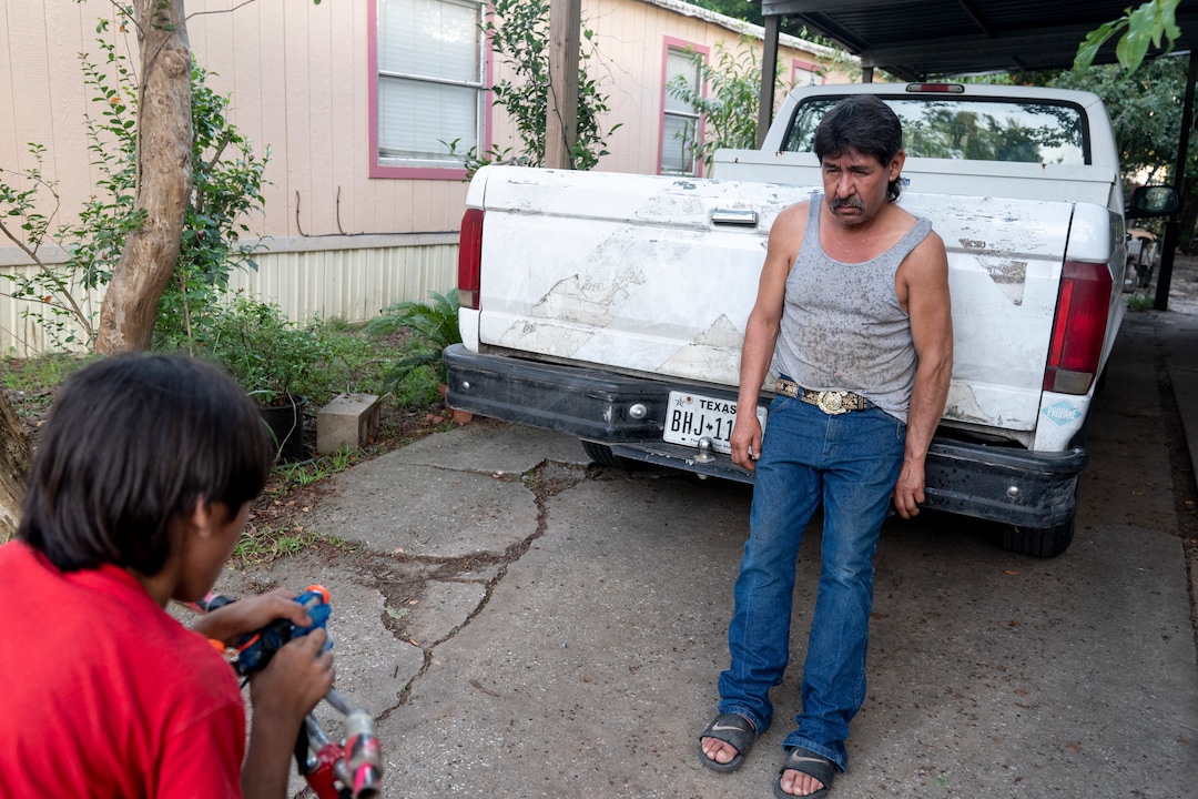 (Ilana Panich-Linsman | The New York Times) Noe Rodriguez, 9, uses a handlebar-mounted squirt gun to cool down his father, Candelario Rodriguez, in Houston, July 23, 2020. Around the world, the poor and marginalized are much more likely to be vulnerable to extreme heat; three of Candelario's co-workers have collapsed from heat exhaustion over the years.