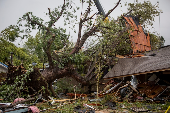 (Benjamin Zack | Standard-Examiner via AP) A tree sits on the Blomquist's home in Washington Terrace, Utah on Friday, Sept. 23, 2016 following Thursday's tornado. Most of the debris in the front yard is from a roof that was torn off another home half a block away.