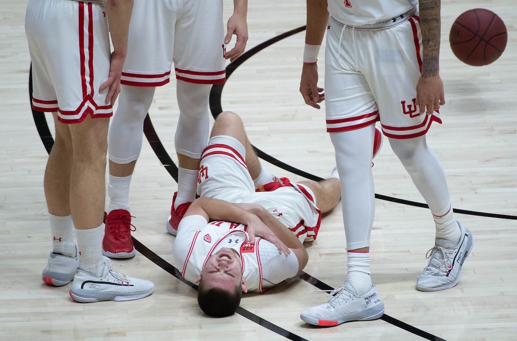 (Francisco Kjolseth | The Salt Lake Tribune) Utah Utes guard Rylan Jones (15) lies on the floor in pain after colliding with USC Trojans forward Chevez Goodwin (1) in PAC-12 basketball action at the Jon M. Huntsman Center, on Saturday, Feb. 27, 2021.
