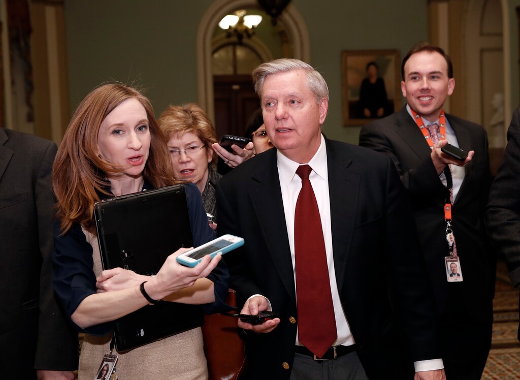 Sen. Lindsey Graham, R-S.C., front right, walks as he is questioned by reporters on Capitol Hill, Friday, Jan. 19, 2018, in Washington. (AP Photo/Alex Brandon)
