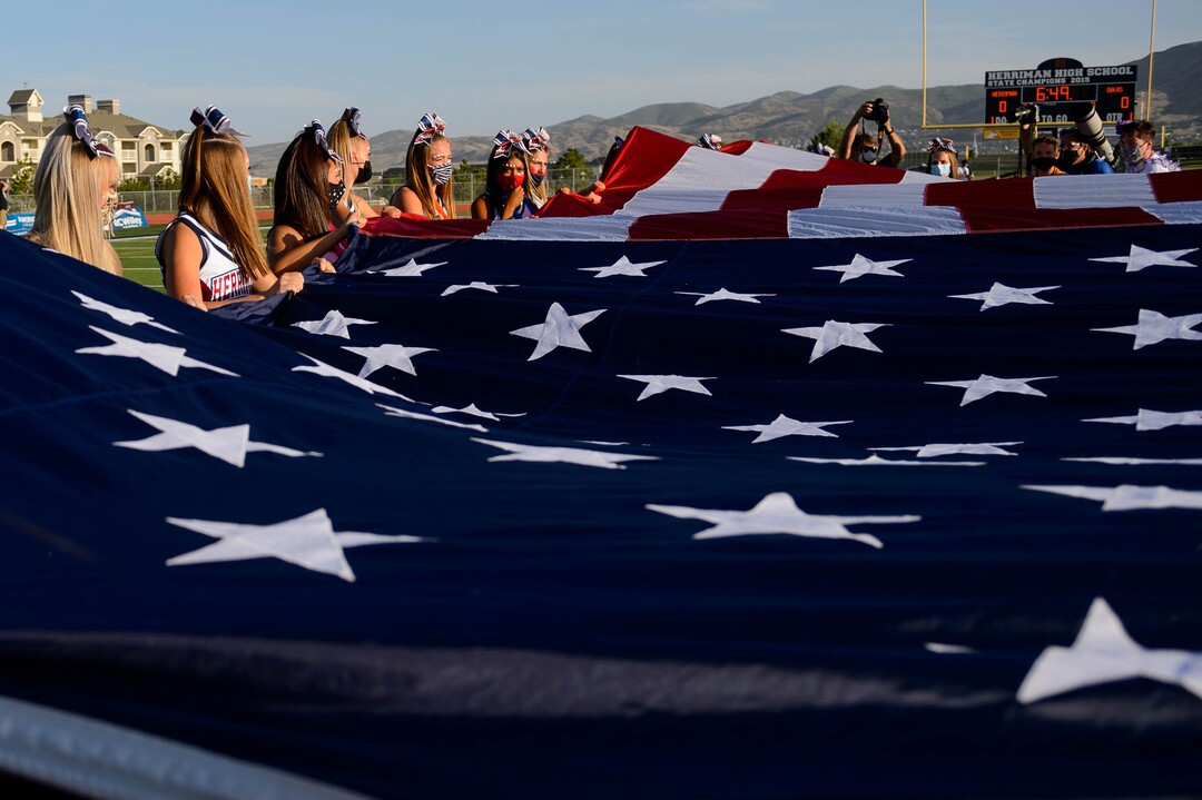 (Trent Nelson  |  The Salt Lake Tribune) Herriman cheerleaders hold a flag during the National Anthem while hosting Davis High School football, in Herriman on Thursday, Aug. 13, 2020.