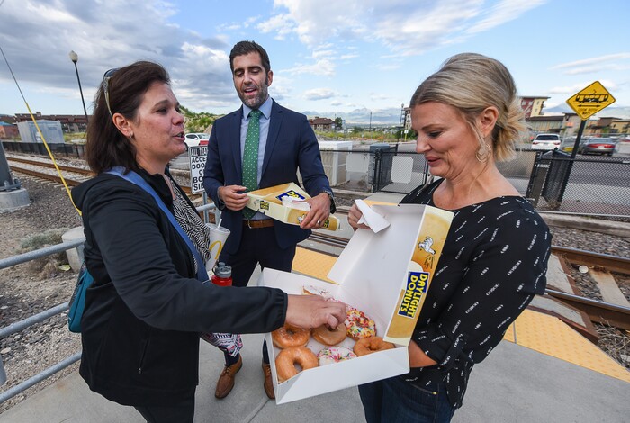 (Francisco Kjolseth | The Salt Lake Tribune) In honor of National Donut Day, Sandy Mayor Kurt Bradburn, center, teams up with Deputy Mayor Evelyn Everton, right, and the Sandy Police Department as morning commuter Pepper Poulsen takes them up on their offer on Friday, June 1, 2018, at the Sandy Civic Center TRAX Station.