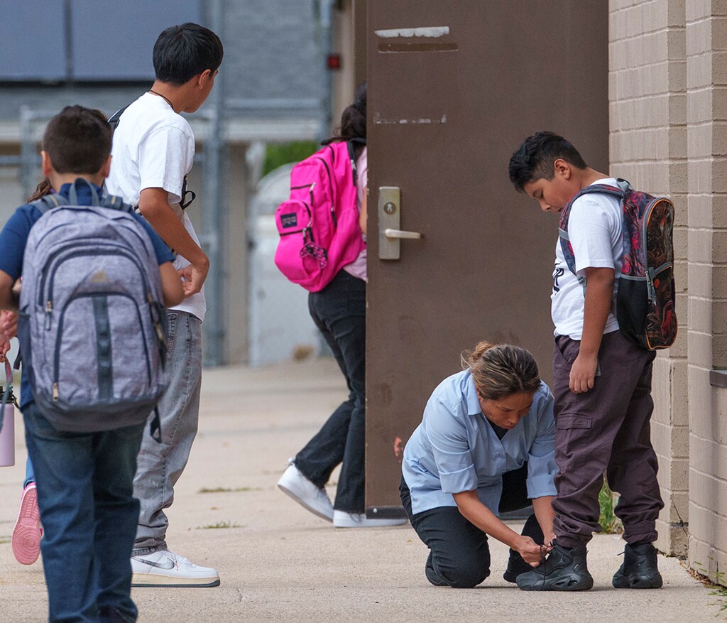 (Leah Hogsten | The Salt Lake Tribune) Gregoria Santillan ties the laces on the tennis shoes of her son Mark Santillian, 8, on the first day of school at Mary W. Jackson Elementary, August 22, 2023.