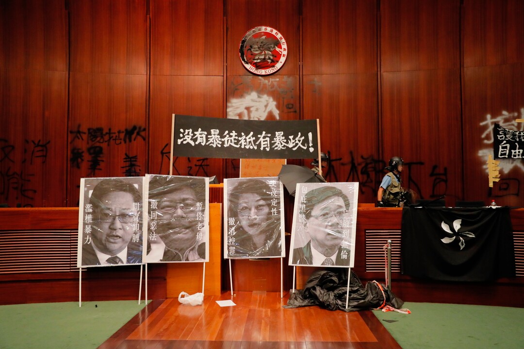 (Kin Cheung | AP Photo) A police officer passes by defaced portraits from left showing, Commissioner of Police Stephen Lo, Hong Kong Chief Executive Carrie Lam, Secretary of Justice Teresa Cheng and Secretary for Security John Lee after authorities take back the meeting hall of the Legislative Council in Hong Kong, during the early hours of Tuesday, July 2, 2019. Hundreds of protesters in Hong Kong swarmed into the legislature's main building Monday night, tearing down portraits of legislative leaders and spray-painting pro-democracy slogans on the walls of the main chamber as frustration over a lack of response from the administration to opposition demands boiled over.