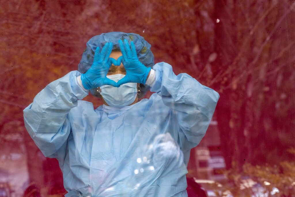 (Mary Altaffer | AP file photo) A nurse gestures from inside the hospital as others hold a demonstration outside Jacobi Medical Center to protest a new policy by the hospital requiring a doctor's note for paid sick leave, Friday, April 17, 2020, in the Bronx borough of New York.