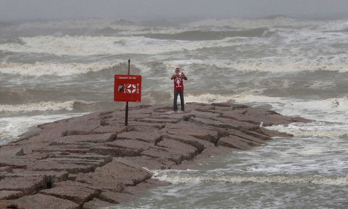 (Jennifer Reynolds | The Galveston County Daily News via AP) Michael Scott uses his smartphone to livestream the rain and storm surge of Hurricane Harvey from the 59th Street rock groin in Galveston, Texas on Saturday, Aug. 26, 2017.