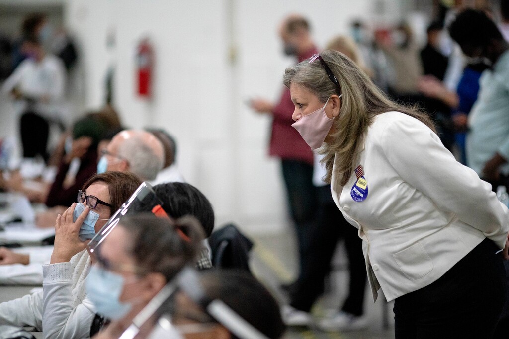 (David Goldman | AP) A Republican election challenger at right watches over election inspectors as they examine a ballot as votes are counted into the early morning hours Wednesday, Nov. 4, 2020, at the central counting board in Detroit.