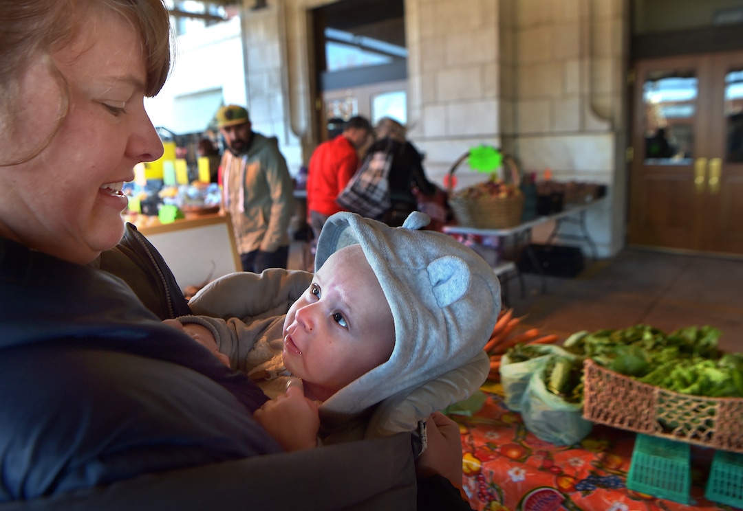 (Scott Sommerdorf   |  The Salt Lake Tribune)   Carly Gillespie holds her four month old son Gus while manning the BUG (Backyard Urban Gardens) Farms booth at the Rio Grande Winter Market, Saturday, November 11, 2017. The market is a project of Urban Food Connections of Utah and will be held every Saturday, through April 21st, from 10 AM - 2 PM.