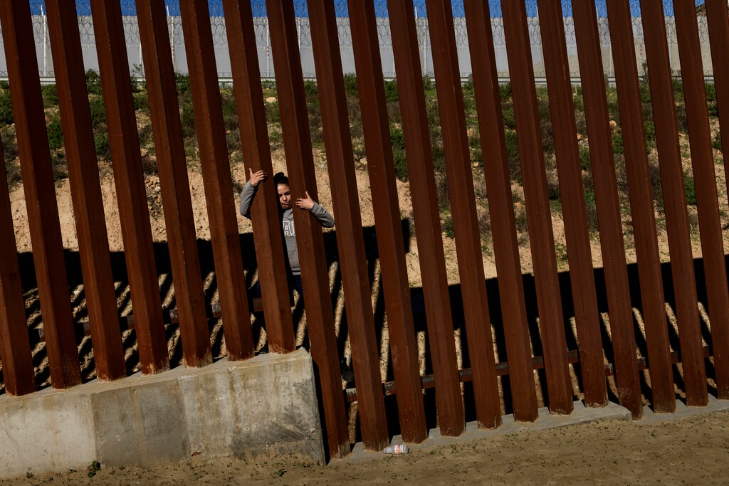 A migrant jumps the border fence to get into the U.S. side to San Diego, Calif., from Tijuana, Mexico, Saturday, Dec. 29, 2018. Discouraged by the long wait to apply for asylum through official ports of entry, many migrants from recent caravans are choosing to cross the U.S. border wall and hand themselves in to border patrol agents. (AP Photo/Daniel Ochoa de Olza)