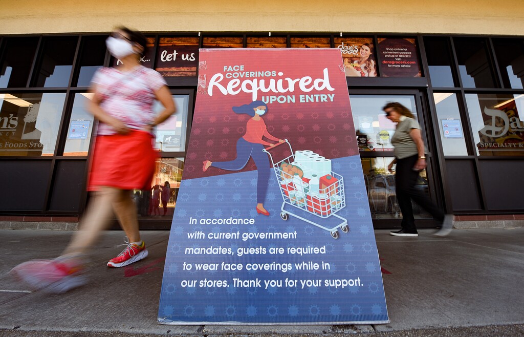 (Francisco Kjolseth  |  The Salt Lake Tribune) Shoppers at Dan's Market in the Foothill Village Shopping Center in Salt Lake City pass a sign requiring masks upon entry on Thursday, July 2, 2020, as the coronavirus continues to surge.