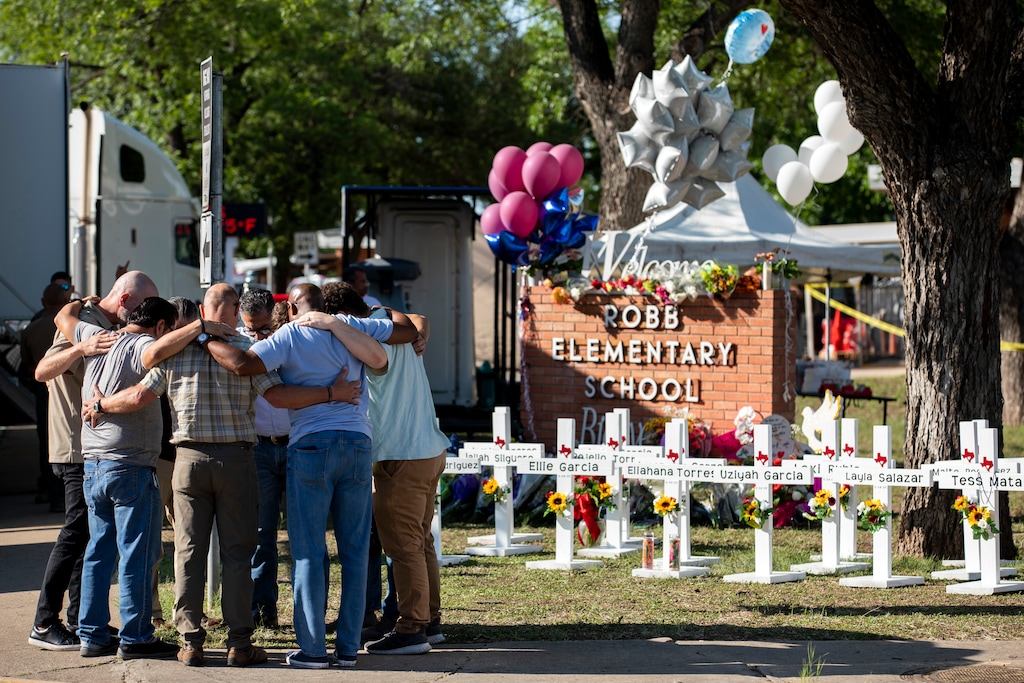 (Ivan Pierre Aguirre | The New York Times) Men pray in front of the makeshift memorial to those killed in Tuesday's mass shooting at Robb Elementary School in Uvalde, Texas, on Thursday, May 26, 2022.