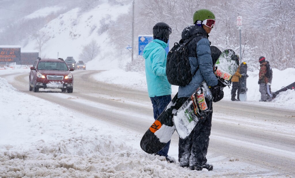 (Francisco Kjolseth | The Salt Lake Tribune) Snowboarders try their luck hitching a ride up Big Cottonwood Canyon on on Wednesday, Feb. 22, 2023. While three resorts in the East have already closed due to poor conditions, Utah is having one of its best seasons ever.