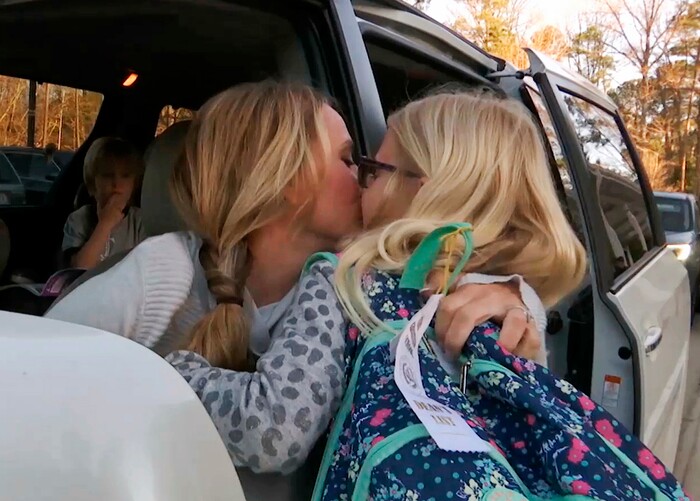 In this Wednesday, March 27, 2019, frame from video, Kacey Ruegsegger Johnson kisses her daughter, Logan, as she drops her off at her school in Cary, N.C. Dropping her kids off at school used to be the hardest part of Ruegsegger Johnson’s day. She would cry most mornings as they left the car, and relied on texted photos from their teachers to make it through the day. (AP Photo/Allen G. Breed)