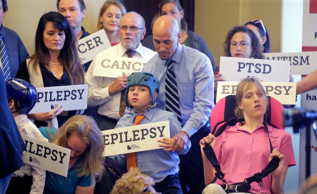 (Rick Bowmer | AP Photo) David Cromar, center, holds his son Holden, 10, who suffers from epilepsy, while standing with other patients, caregivers and supporters during the Utah Patients Coalition news conference Monday, June 26, 2017, in Salt Lake City. A group of activists and Utah residents with chronic conditions launched a ballot initiative to ask voters next year to pass a broad medical marijuana law.