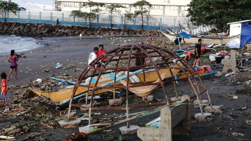 (AP) Residents walks beside an outrigger and playground equipment that were damaged by Typhoon Phanfone along a coastline in Ormoc city, central Philippines on Thursday Dec. 26, 2019. The typhoon left over a dozen dead and many homeless.