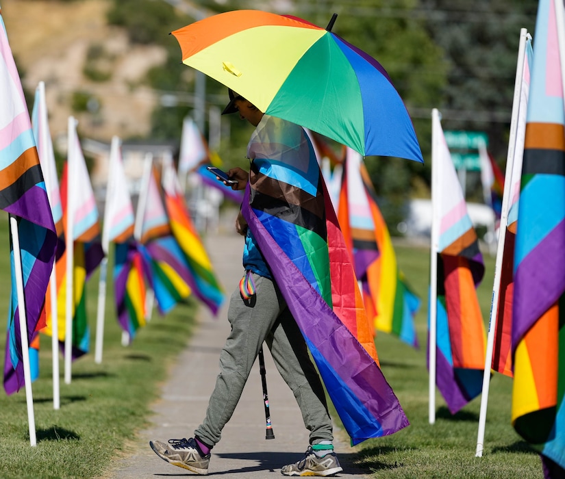 (Francisco Kjolseth | The Salt Lake Tribune) Volunteer Juno Heath walks amongst the pride flags as the RaYnbow Collective hosts a Back to School Pride Night for BYU students at Kiwanis Park in Provo on Saturday, Sept. 3, 2022.