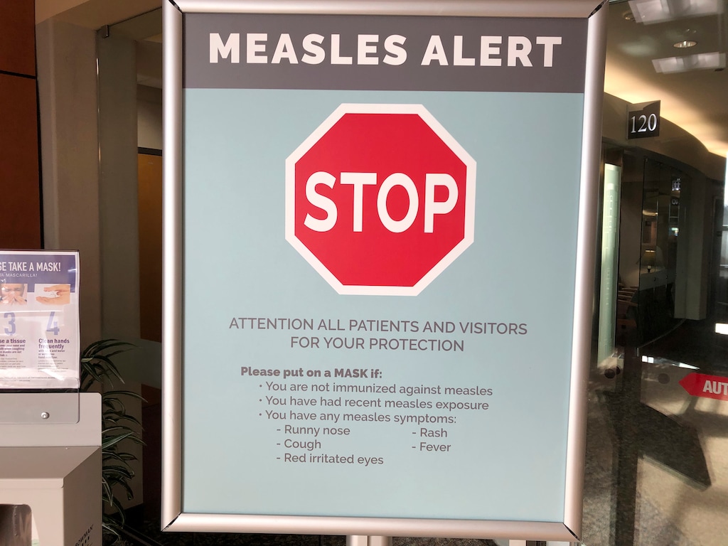 (AP Photo/Gillian Flaccus,File) In this Jan. 30, 2019 file photo signs posted at The Vancouver Clinic in Vancouver, Wash., warn patients and visitors of a measles outbreak. A measles outbreak near Portland, Ore., has revived a bitter debate over so-called personal belief exemptions to childhood vaccinations. Four percent of Washington secondary school students have non-medical vaccine exemptions.