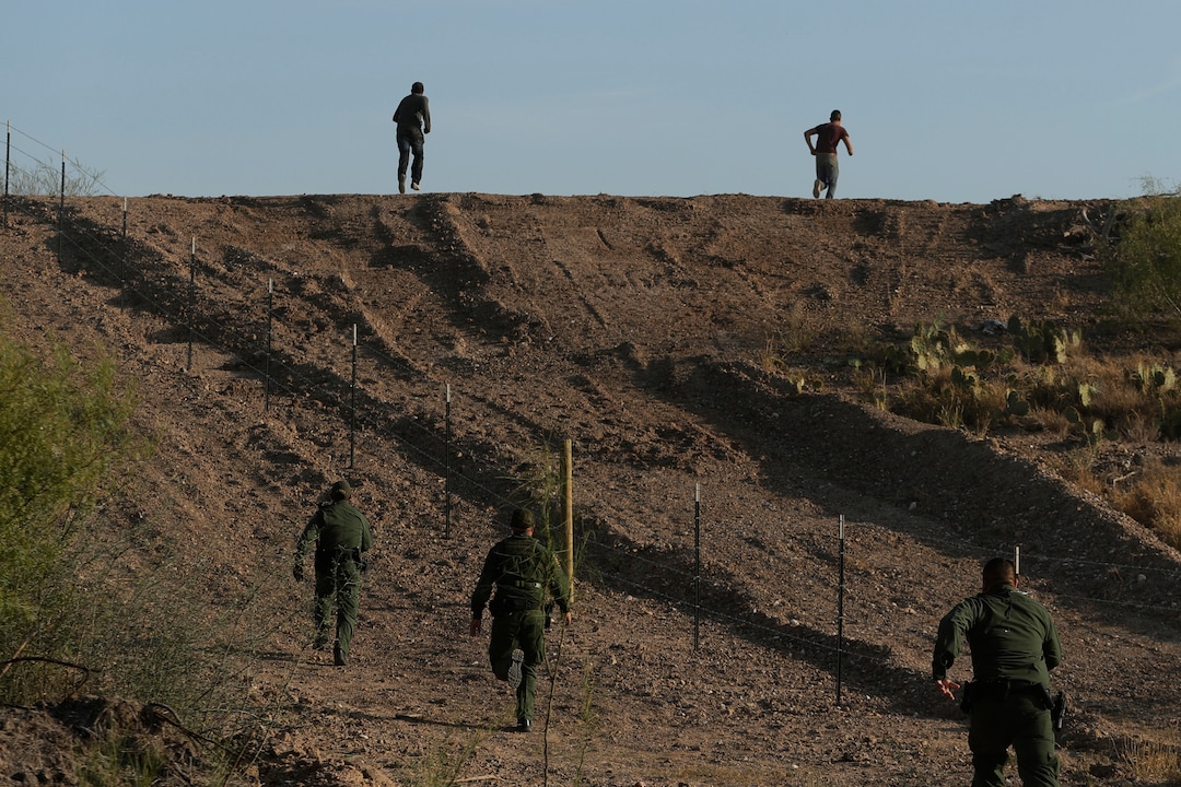 In this Wednesday, Nov. 6, 2019, photo, Border Patrol agents chase two men thought to have entered the country illegally, near McAllen, Texas, along the U.S.-Mexico border. (AP Photo/Eric Gay)